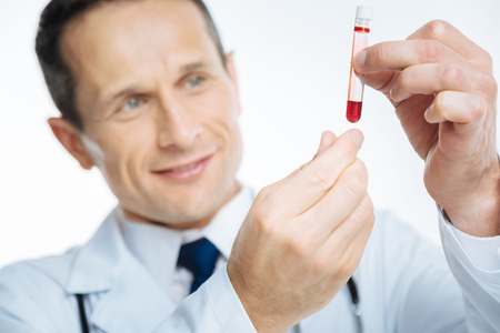 Smiling doctor looking at blood sampleの写真素材