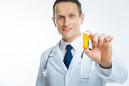 Smiling physician showing plastic bottle full of pillsの写真素材