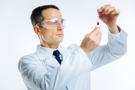 Intellectual doctor looking at test tube with blood sampleの写真素材