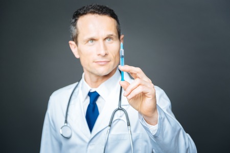 Confident male doctor focusing his attention on syringeの写真素材