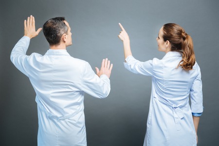 Turned back colleagues pretending to touch invisible screenの写真素材