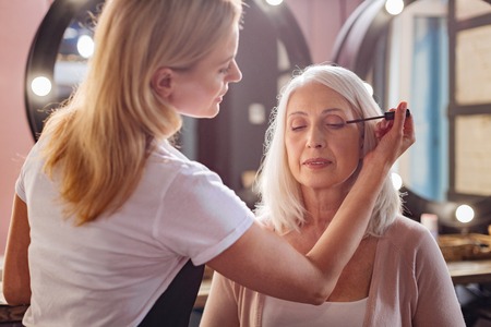 Petite makeup artist applying mascara to her clients eyelashesの写真素材