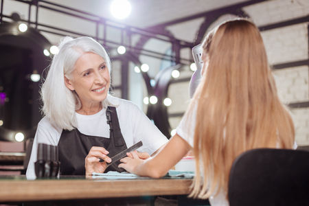 Senior manicurist listening to her teenage clients storyの写真素材