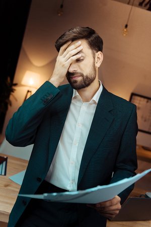 Tired male person covering his faceの写真素材