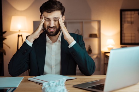 Tired man touching his foreheadの写真素材