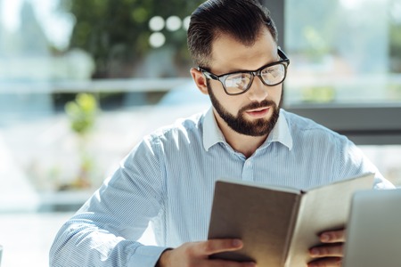 Handsome man examining notebook with his scheduleの写真素材