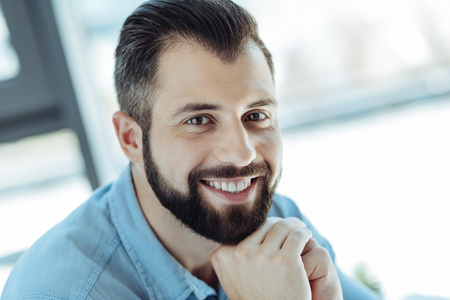Cheerful man resting his chin on hands and smilingの写真素材