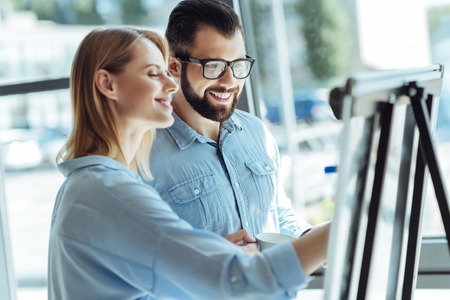 Cheerful colleagues writing on whiteboard in officeの写真素材
