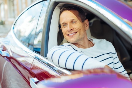 Happy delighted man sitting in his carの写真素材