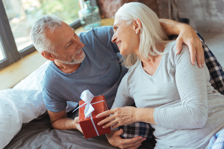 Positive aged loving couple holding a presentの写真素材