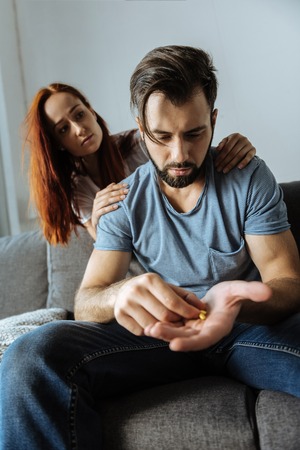 Unhappy sympathetic woman sitting behind her husbandの写真素材