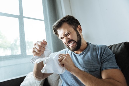 Furious angry man tearing a sheet of paper to piecesの写真素材