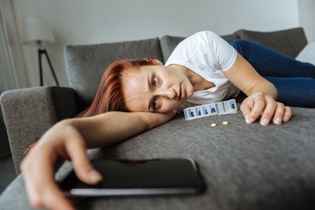 Sad exhausted woman holding her smartphoneの写真素材