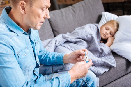 Concerned father checking temperature of his sick sonの写真素材