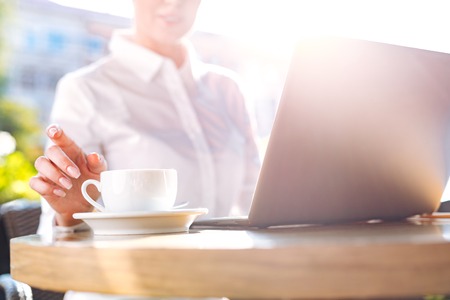 Neat female hand reaching for a cup of coffee in cafeの写真素材