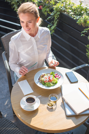 Beautiful woman having salad in a restaurantの写真素材