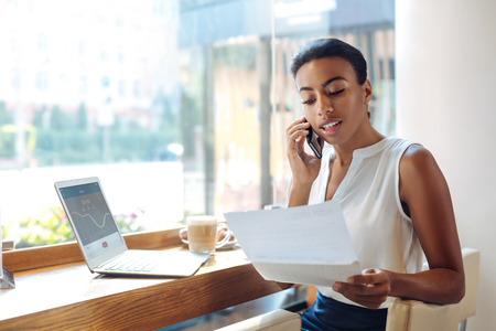 Charming woman discussing research results on the phoneの写真素材