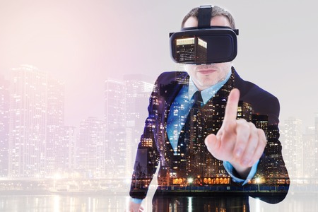 Businessman in VR headset posing against night city backgroundの写真素材