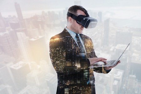 Bristled businessman in VR headset working on laptopの写真素材