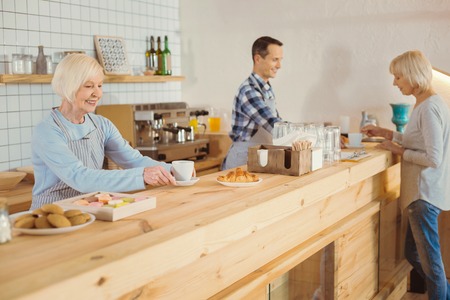 Delighted positive woman serving coffee