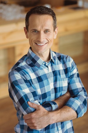 Pleasant cheerful man standing cross handedの写真素材