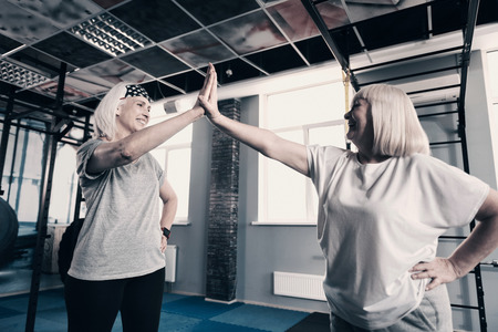 Two senior women high-fiving each other in gymの写真素材