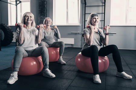 Elderly women working out with dumbbells on exercise ballsの写真素材