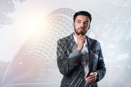 Thoughtful man. Clever young cheerful man wearing an elegant suit and looking thoughtfulの写真素材