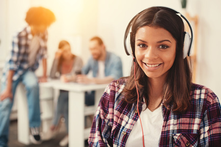 Only positive. Delighted smiling young student looking happy while listening to music in big headphonesの写真素材