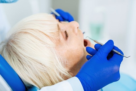 Be patient. Close up of patient sitting on the dental chair while professional stomatologist curing her teethの写真素材