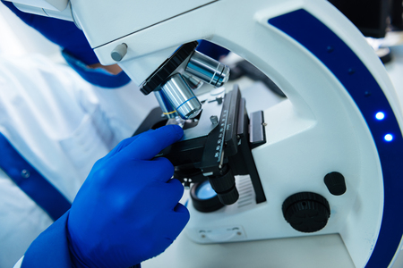Researcher wearing a uniform and medical gloves and sitting at a modern advanced cutting-edge...