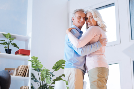 Low angle shot of an adorable couple standing close to each other and smiling while embracing in a dance.の写真素材