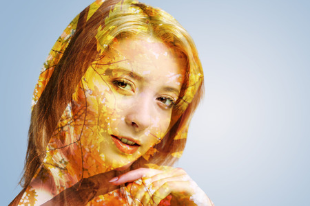 Scaled up portrait of a young blonde woman looking into the camera dreamily while posing against the autumnal background.の写真素材