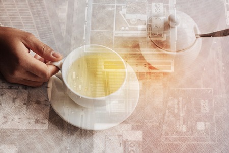 Young relaxing person having a good time while sitting at the table and holding a cup of tasty hot teaの写真素材