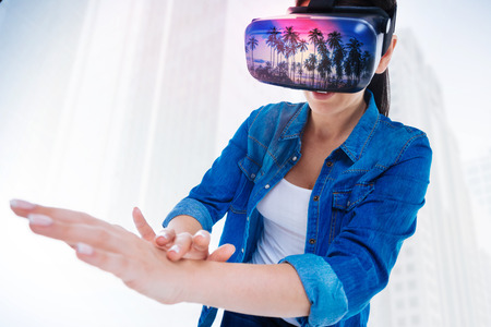 Fantastic feeling. Good looking optimistic appealing woman  testing VR glasses while touching her...