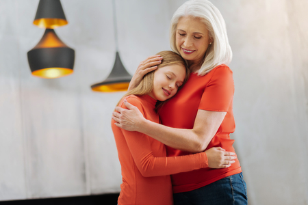 My girl. Nice positive caring woman hugging her granddaughter and smiling while caring about herの写真素材