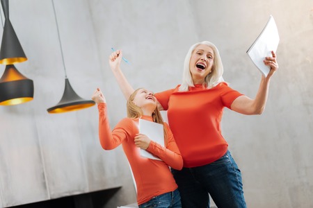 We did it. Joyful nice delighted grandmother and granddaughter laughing and expressing their emotions while feeling happyの写真素材