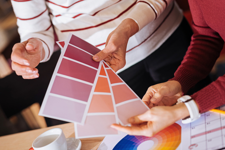 Color palette. Creative enthusiastic designers choosing an appropriate color while holding three beautiful color palettesの写真素材