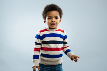 I am shocked. Amazing African boy opening mouth and looking straight while standing over grey backgroundの写真素材