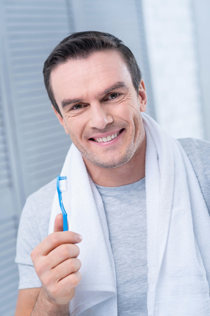 Shiny smile. Prosperous nice young man carrying toothbrush smiling to the camera and preparing for going outの写真素材