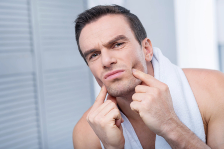 Small chicks. Pleasant appealing young man  pushing his chicks  while looking straight and making grimaceの写真素材