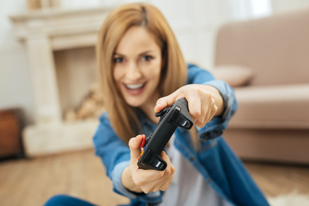 Play with me. Lovely vigorous blond young woman smiling and playing a game while sitting on the...