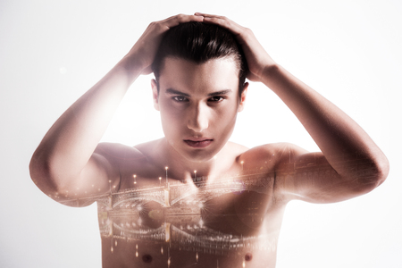 Creative concept. Nice handsome good looking man holding his hands up and touching his head while looking in front of himの写真素材