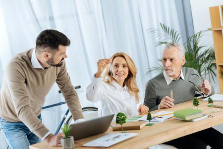Important seeds. Smart excited enthusiastic ecological activist feeling not indifferent while showing a test tube with significant seeds to her colleaguesの写真素材