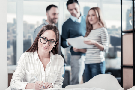 Im a professional. Pleasant cute occupied woman holding a pan writing and looking straight.の写真素材
