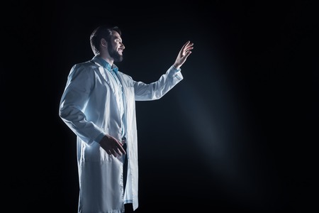 My success. Cheerful professional handsome scientist smiling and suing new technology while standing...
