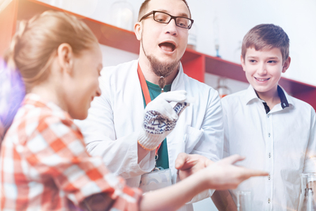 Abracadabra. Up and coming teacher of chemistry pretending to be a real magician while playing with a different aged group of pupils and trying to show them that science can be fun.の写真素材