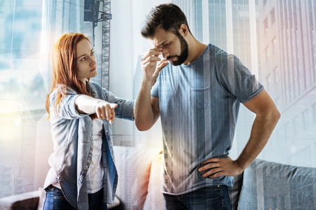 Go away. Young tired offended woman looking at her guilty boyfriend and showing him the way to leaveの写真素材