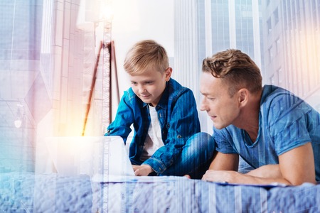 Attentive male person bowing head and crossing legs while working at computerの写真素材
