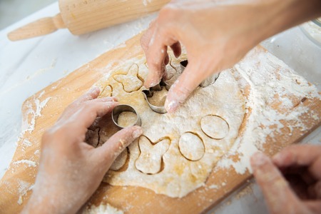 Molds for baking. Loving nice little girl making some cookies and using cute molds while her mom helping herの写真素材